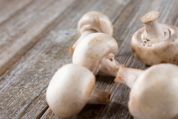 A view of several button mushrooms on a wooden table surface.