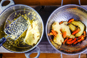 Fresh ginger is grated into a big pot.
