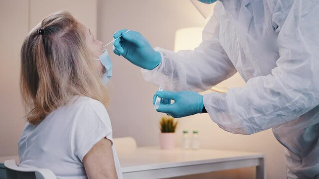 Doctor performing nasal swab covid test on an elderly woman. High quality 4k footage