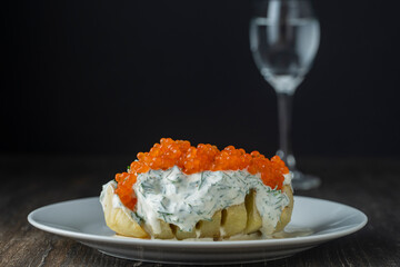 Baked potato with creamy cheese sauce flavoured with dill and red salmon caviar