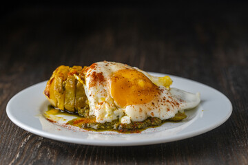 Baked potato with fried egg in white plate, close up