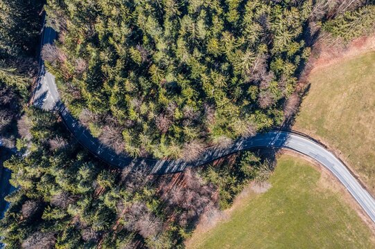 Bild einer Luftaufnahme mit einer Drohne einer Straße im dicht bewachsenen Nadelbaum Wald im Frühling Frühjahr mit Autos, Deutschland