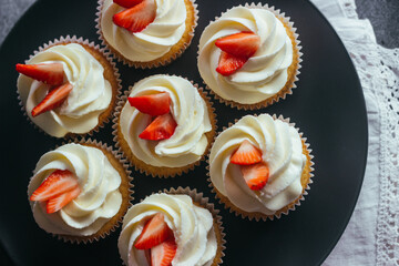 Delicious cupcakes. Cupcakes with cream cheese and strawberries. Cupcakes on a concrete table 