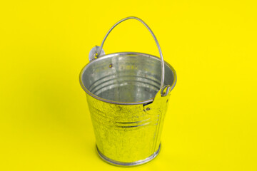 Empty metal bucket on a yellow background close-up.