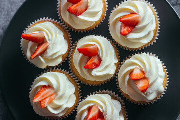 Delicious cupcakes. Cupcakes with cream cheese and strawberries. Cupcakes on a concrete table 
