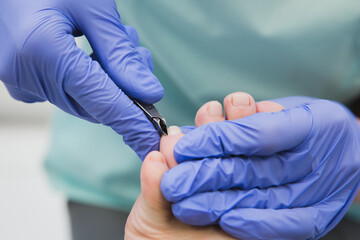 Hygienic pedicure procedure. Pedicurist treats client's nails with tweezers.