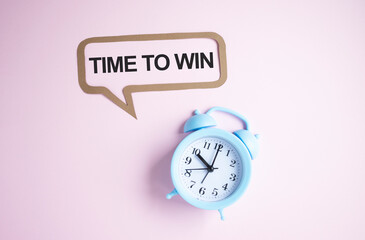 TIME TO WIN. Text on white sheet of notepad on white background near table clock