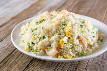 A view of a plate of fried rice, featuring egg and shrimp.