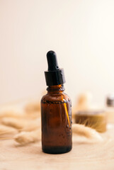 Glass cosmetic brown bottle with a dropper on a beige background with dry flowers . The concept of natural cosmetics, natural essential oil