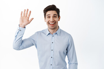 Friendly office worker waving hand and saying hello, smiling say hi, greeting, making warm welcome and looking cheerful, standing against white background - 424245905