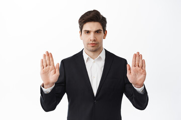 Stop, keep your distance. Serious and determined businessman in black suit show block, refusal or...