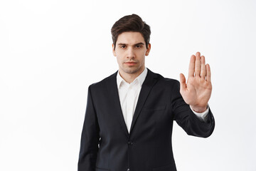 Stop, stay away, keep distance. Serious businessman, man in black suit stretch out hand to block,...