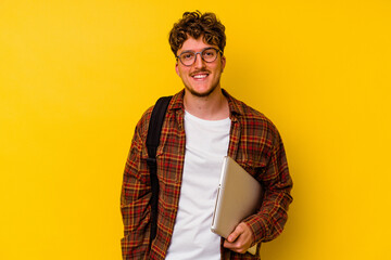Young student caucasian man holding a laptop isolated on yellow background happy, smiling and cheerful.