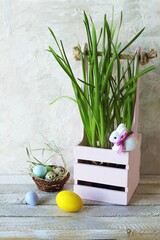 Easter eggs, spring plants, toy hares on a light background, home interior decoration for the holiday