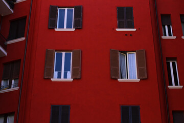 Cherry red residential building in Rome, blue sky.