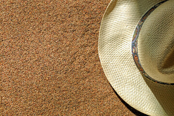 Fototapeta na wymiar Sand and straw hat top view, summer background with copy space