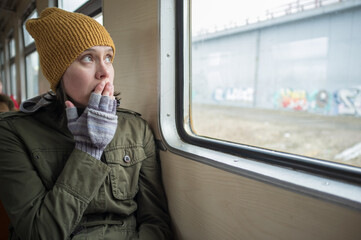 Frightened woman traveling in a train and looking out the window, she was lost or forgot something.