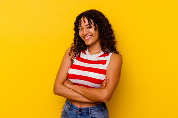 Young mixed race woman isolated on yellow background who feels confident, crossing arms with determination.