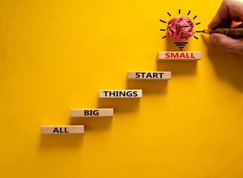 Business concept growth success process. Wood blocks stacking as step stair on yellow background, copy space. Businessman hand. Words 'all big things start small'. Conceptual image of motivation.