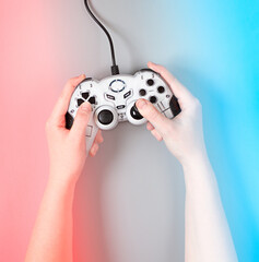 Female hands with a game joystick on blue and red background © lens7 
