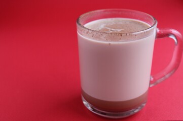Cocoa hot chocolate in a glass mug on a red background with room for text copyspace and liver on hellish plan