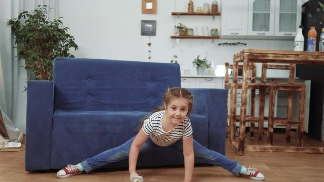 little child daughter a sing dancing at home. stay home active leisure happy childhood concept. child daughter dancing sing next to dream the sofa with a microphone. kid dream dance