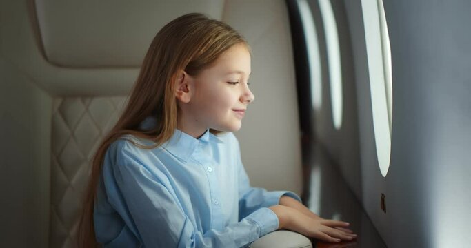Child sitting in airplane seat and looking at window.