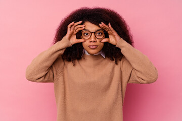 Young african american woman isolated on pink background keeping eyes opened to find a success opportunity.