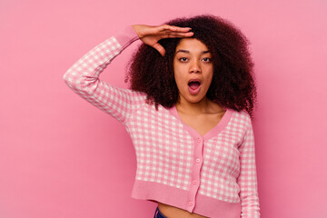 Young african american woman isolated on pink background shouts loud, keeps eyes opened and hands tense.