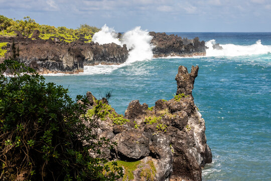 Powerful waves crash into the formations in the volcanic rock at Waianapanapa State Park on the north shore of Maui near Hana, Hawaii
