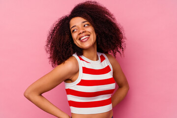 Young african american woman isolated on pink background laughs happily and has fun keeping hands on stomach.