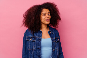 Young african american woman isolated on pink background shrugs shoulders and open eyes confused.
