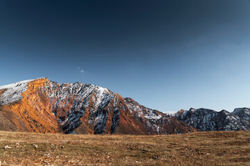 Amazing bright yellow rocks snow covered . 
Panoramic view on rocks and field on the bright sunny day with clear blue sky.