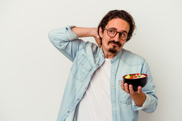 Young caucasian man eating a ramen isolated on white background touching back of head, thinking and making a choice.