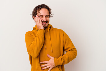 Fototapeta premium Young caucasian man isolated on white background laughs happily and has fun keeping hands on stomach.