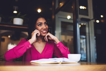 Happy black woman with hand at chin talking on phone
