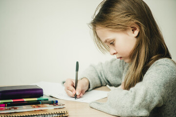 teen girl writing at the table on a white background