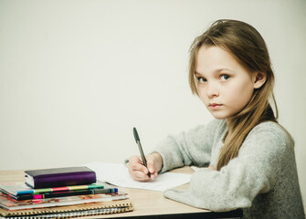 teen girl writing at the table on a white background