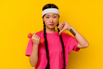 Young sport chinese woman isolated on yellow background showing a dislike gesture, thumbs down....
