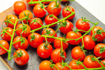 Covered with drops of water, fresh tomatoes with sprigs on wood