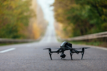 At the autumn dawn, a drone flies over the asphalt road going into the distance