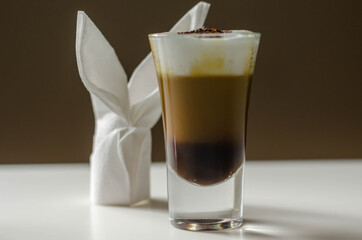 Coffee drink shot with a nutty note with fluffy milk foam, decorated with chocolate shavings, served with an Easter bunny-shaped napkin