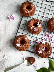 Baking, lilac, spring. Delicious sweet chocolate cupcakes with cream on top. Filled with chocolate. Surrounded by fresh lilacs. On a concrete countertop. Grey background. Space for the text. Content.
