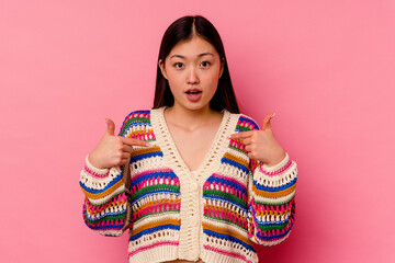 Young chinese woman isolated on pink background points down with fingers, positive feeling.