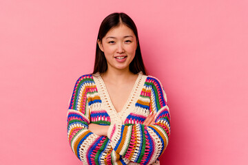 Young chinese woman isolated on pink background who feels confident, crossing arms with...