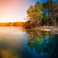 Rainbow Clouds over the Tranquil Forest Pond. Sun Ray Reflections to Glowing Clouds. Mysterious Weather on Cape Cod in March.