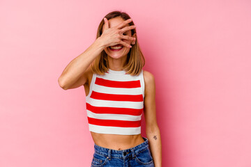 Young caucasian woman isolated on pink background covers eyes with hands, smiles broadly waiting for a surprise.