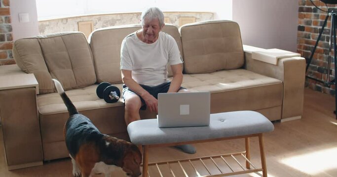 adult man and mature senior working his body with dumbbell - one man hapy training indoors sitted on the sofa. High quality 4k footage