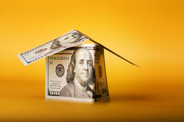 House Made from 100 dollar bills Cash Money on Yellow Background.