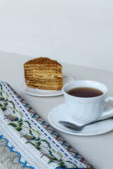 White cup of tea and a piece of honey cake. Vertical photography.